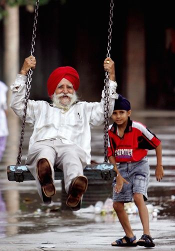 A Sikh child pushes his grandfather on a swing in a park in the northern Indian city Chandigarh August 13, 2006. REUTERS/Kamal Kishore     (INDIA)